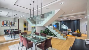 Un salon moderne avec une table à manger en verre, des chaises rouges, un escalier et un téléviseur.