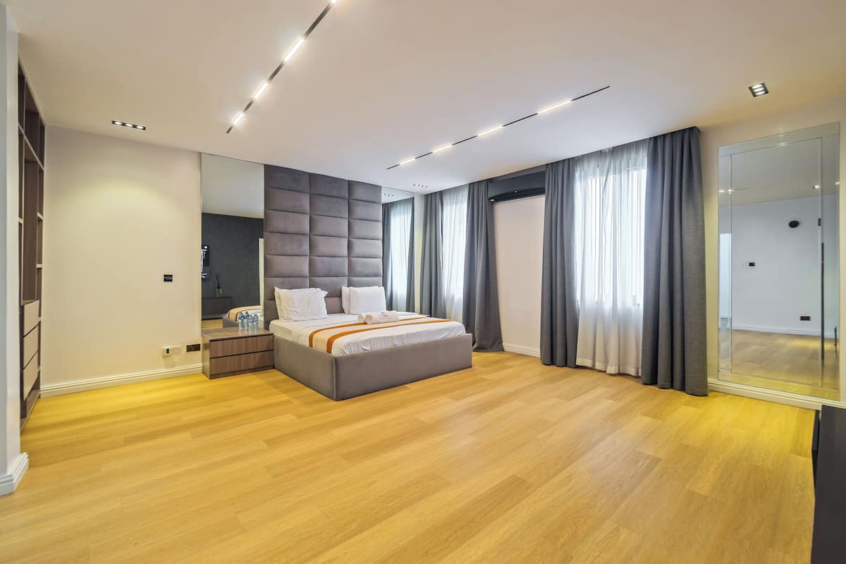 A modern bedroom with a large bed, a built-in wardrobe, and a large mirror.