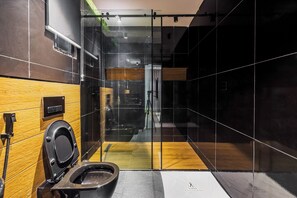 Une salle de bain moderne avec une paroi de séparation en verre, un meuble-lavabo en bois et des toilettes noires.
