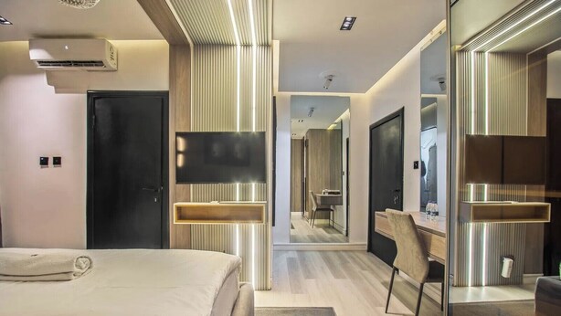 Une chambre d’hôtel moderne équipée d’un lit, d’un bureau, d’un miroir et d’une télévision.