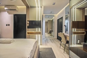 A modern hotel room with a bed, a desk, a mirror, and a television. - Avenue Montaigne (Lagos)