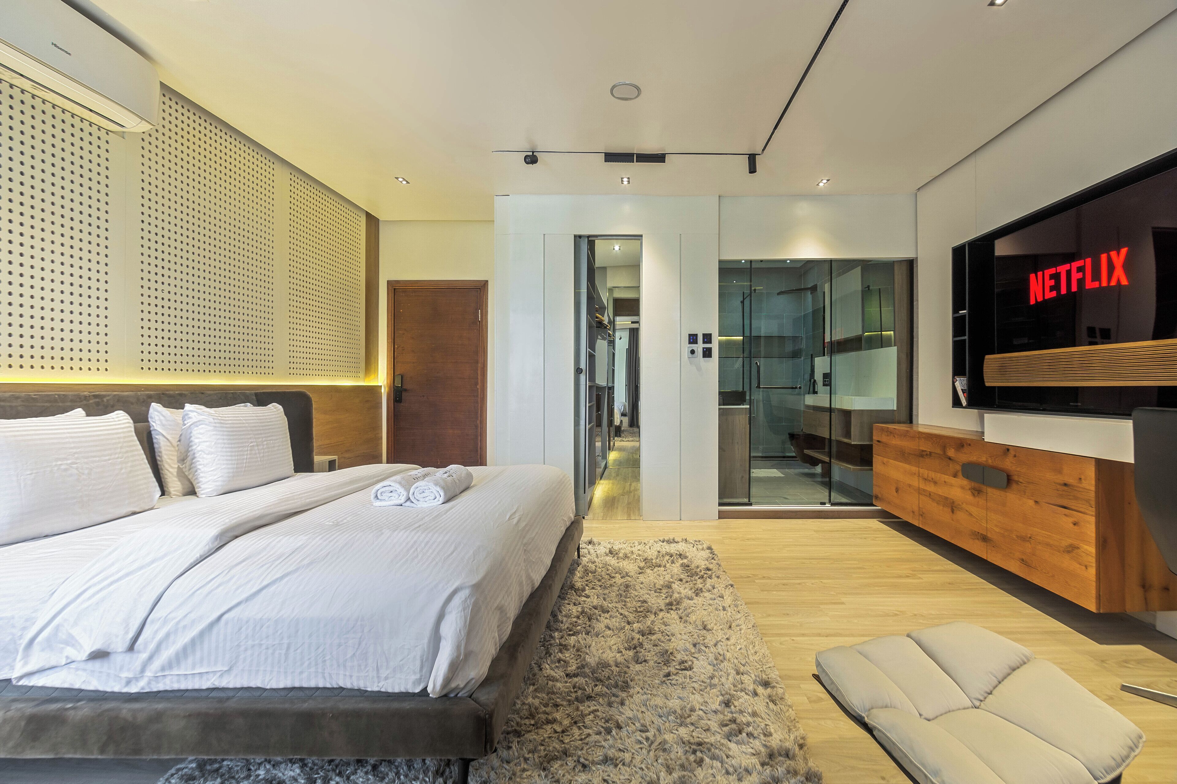 A modern bedroom with a large bed, a TV, and a wooden cabinet.