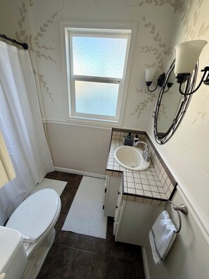 Un bagno con il water, un lavandino, una finestra e un portascopino.