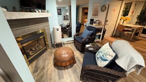 A cozy living room with a fireplace, wicker furniture, and a dining area with a table and chairs.