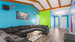 Una sala de estar con un sofá modular, una mesa de centro y un cuadro en la pared.