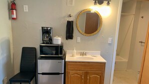 Una kitchenette compacta con refrigerador, microondas, cafetera y lavamanos.