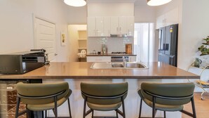Een moderne keuken met een centraal eiland, roestvrijstalen apparatuur en barkrukken.
