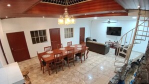 Un comedor con mesa y sillas de madera, una araña y una pared de piedra con una sección de azulejos azules.