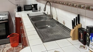 Una cocina con armarios de madera, un lavamanos de acero inoxidable y salpicadero de azulejos.