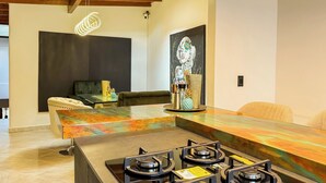 Eine moderne Küche mit farbigem Arbeitsplatz, einem Gasherd und einem Essbereich mit einer Couch und einem Couchtisch.
