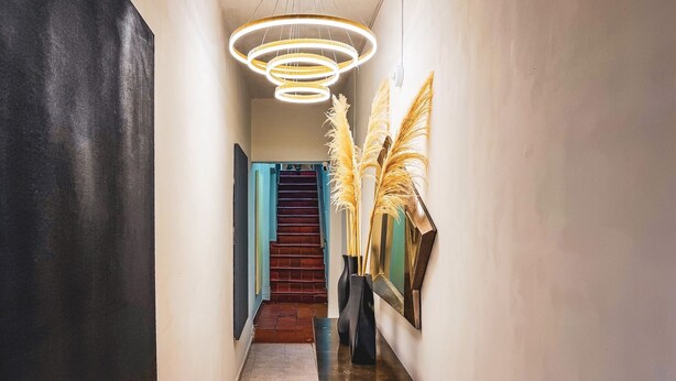 Ein Flur mit Treppe, einer modernen Leuchte und Zimmerpflanzen.