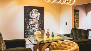 Ein modernes Wohnzimmer mit einem Glastisch, zwei Sesseln und einem großen abstrakten Gemälde an der Wand.