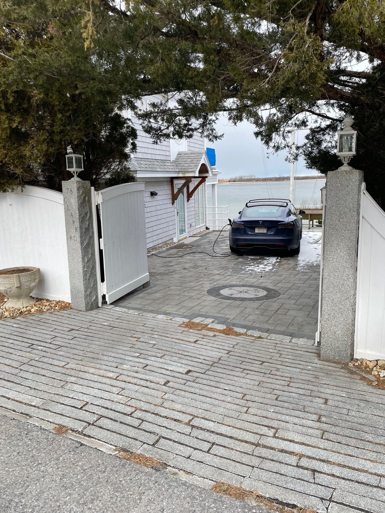A gated driveway leading to a house with a parked car.