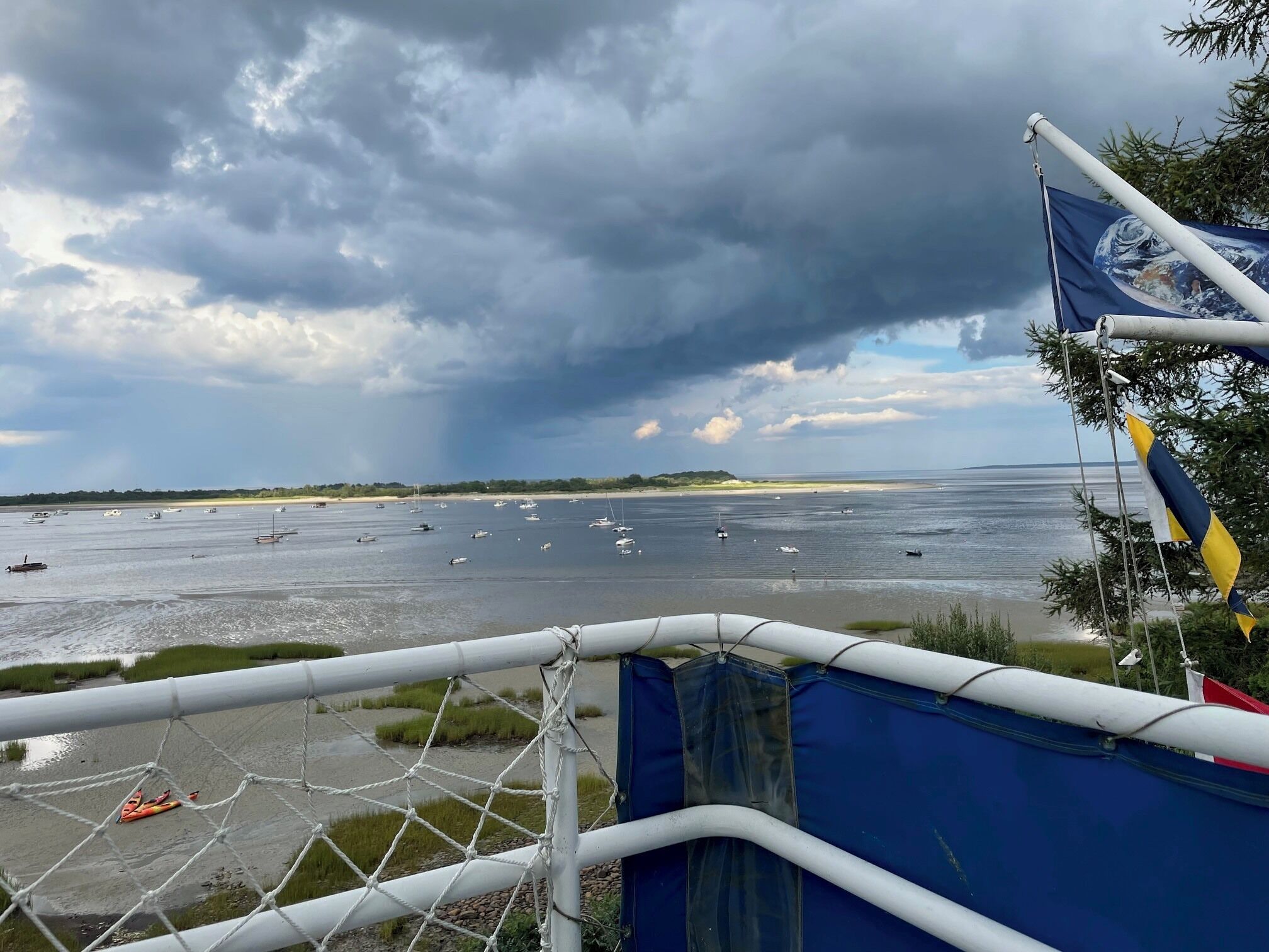 A coastal view with a beach, boats, and a cloudy sky.