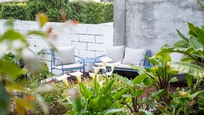 Eine Gartenpatio mit einem blauen Metalltisch und weiß gepolsterten Sitzgelegenheiten.
