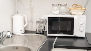 Eine Küche mit einer weißen Mikrowelle, einer Kaffeemaschine und einem Spülbecken.