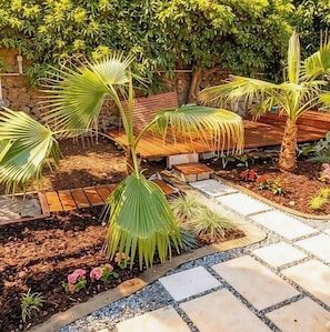 A garden area with palm trees, a stone pathway, wooden benches, and a stone wall. - Guest Suite ("Baleias") near PDL (Sao Roque)