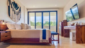 A bedroom with a bed, a desk, a television, and a large window. - Modern 2BR Apartment in Tulum Great Location (Tulum)