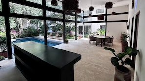 A modern interior with a pool, outdoor seating, and a dining area. - Modern 2BR Apartment in Tulum Great Location (Tulum)
