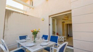 Un comedor con una mesa dispuesta para cuatro, sillas, un florero con flores y una puerta que da a otra habitación.