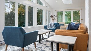 A bright room with large windows, a skylight, and a cozy seating area with a sofa and chairs. - Oceanfront Acadia Views Arcade Game Room Pets Ok (Surry)