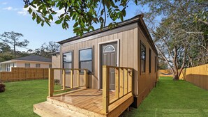 A small wooden cabin with a front porch and a deck, surrounded by a well-maintained lawn and a wooden fence. - Quiet Milton Retreat Close to Downtown & Water! (Milton)