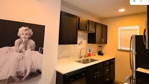 A kitchen with dark cabinets, a white countertop, a stainless steel dishwasher, and a refrigerator. - Reagan 206: 2-bedroom apartment in  Dallas neighborhood (Dallas)