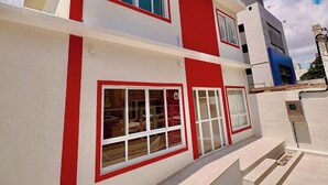 Un edificio moderno de dos pisos con una combinación de colores rojo y blanco, ventanas grandes y techo plano.