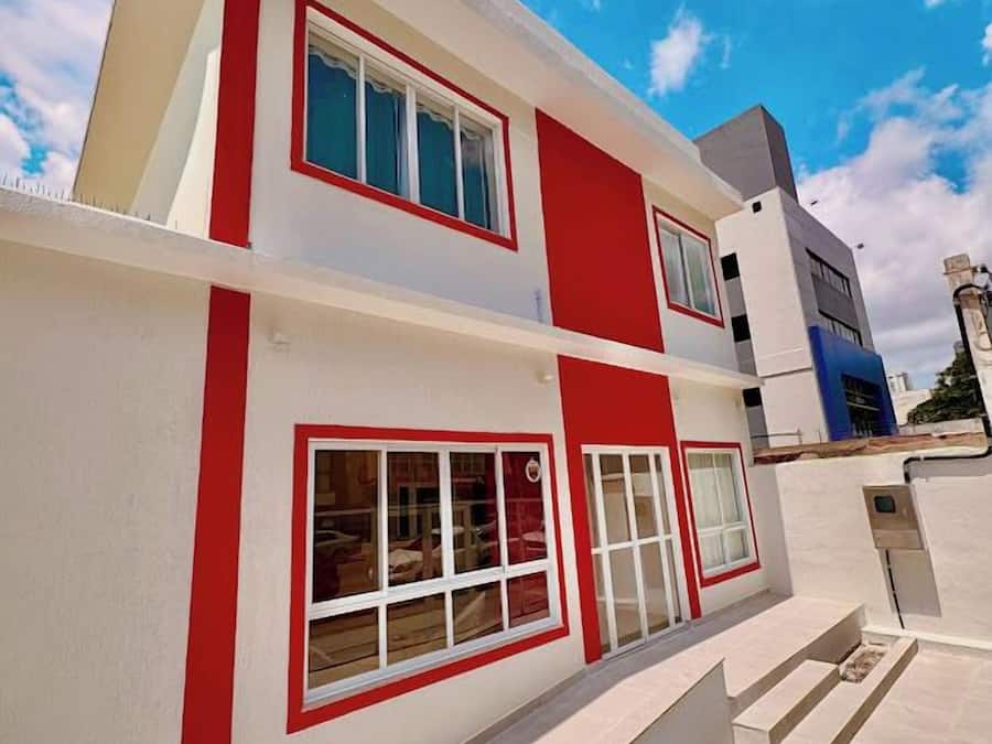 A modern two-story building with a red and white color scheme, large windows, and a flat roof.
