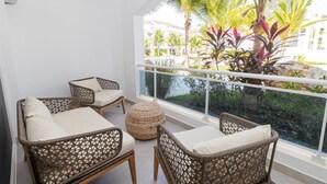 A balcony with wicker furniture and a view of palm trees and buildings. - Elegant 1-BD Luxury Escape in Paradise in Estrella (Dominicus)