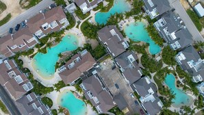 An aerial view of a resort with multiple swimming pools, connected by walkways, surrounded by residential buildings and palm trees. - Elegant 1-BD Luxury Escape in Paradise in Estrella (Dominicus)