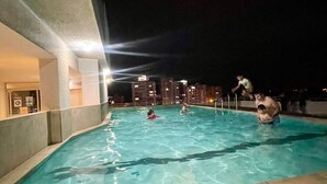 Une piscine la nuit, avec des gens qui nagent et s'amusent.