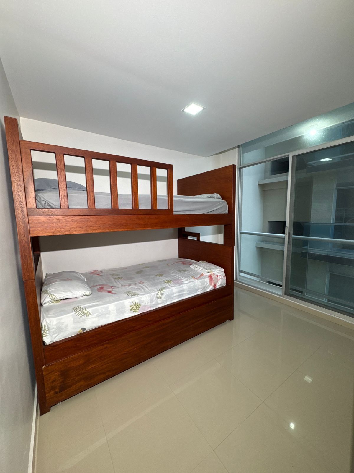 Uma cama beliche com estrutura de madeira e uma cama inferior com colcha florida.