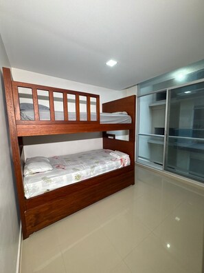 A bunk bed with a wooden frame and a lower bed with a floral bedspread. - Beautiful apartment in Tonsupa / 2 pools / air conditioning / elevator (Tonsupa)