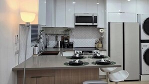 A modern kitchen with white cabinets, a central island with bar stools, a microwave, a stove, and a refrigerator. - Cozy house+close to Glendale,Pasadena,DT & K-Town (La Crescenta-Montrose)