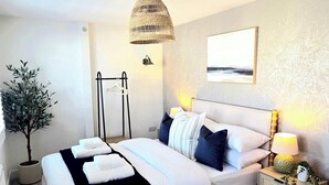 A bedroom with a bed, bedside tables, a hanging light, a potted plant, and a wall-mounted artwork. - Vibrant 4BR | 2Bath | Home |High-end |Cntr Cheltenham |All stays | Parking incl (Cheltenham)