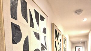 A hallway with wooden flooring, white walls, and abstract art on the left. - Vibrant 4BR | 2Bath | Home |High-end |Cntr Cheltenham |All stays | Parking incl (Cheltenham)