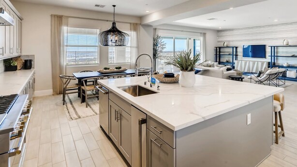 A modern kitchen with a large island, stainless steel appliances, and a dining area with a blue table and chairs. - Luxe Desert Escape w/ Strip View - 360° Las Vegas Strip & Mountain Views (Henderson)