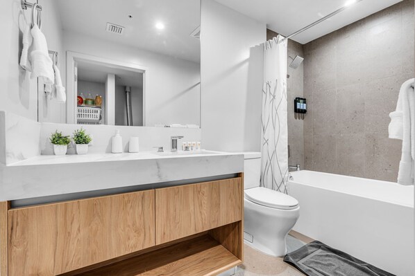 Une salle de bain moderne avec un meuble-lavabo blanc, un meuble en bois et une douche avec rideau.