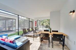 En moderne udendørs terrasse med spiseplads, loungesenge og udsigt til poolen.