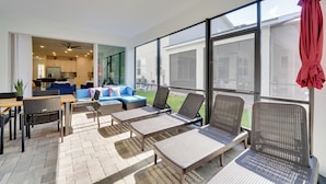 Eine sonnendurchflutete Terrassenfläche mit Korbsessel-Loungemöbeln, einem Esstisch und einem blauen Sofa.