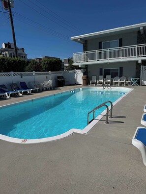 A swimming pool with numbered lounge chairs, a pool ladder, and a white fence. - Studio Condo 2 Blocks to Beach and Boardwalk, Pool and Designated Parking (Ocean City)