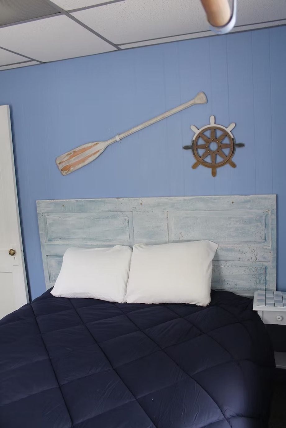 Una cama con colcha azul marino, almohada blanca y cabecera de madera.