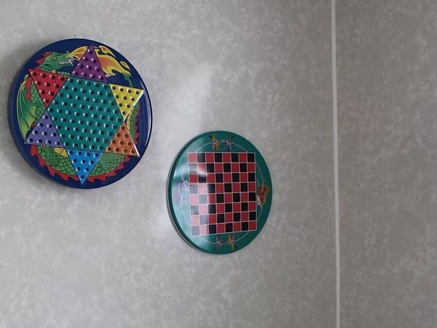 Un baño con inodoro, un dispensador de papel higiénico y dos placas decorativas en la pared.