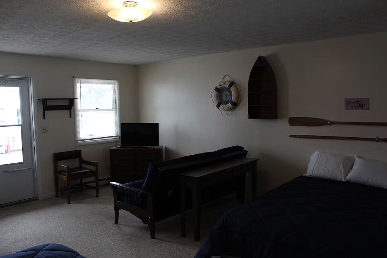 Een slaapkamer met een bed, een bureau, een stoel, een televisie en een raam.