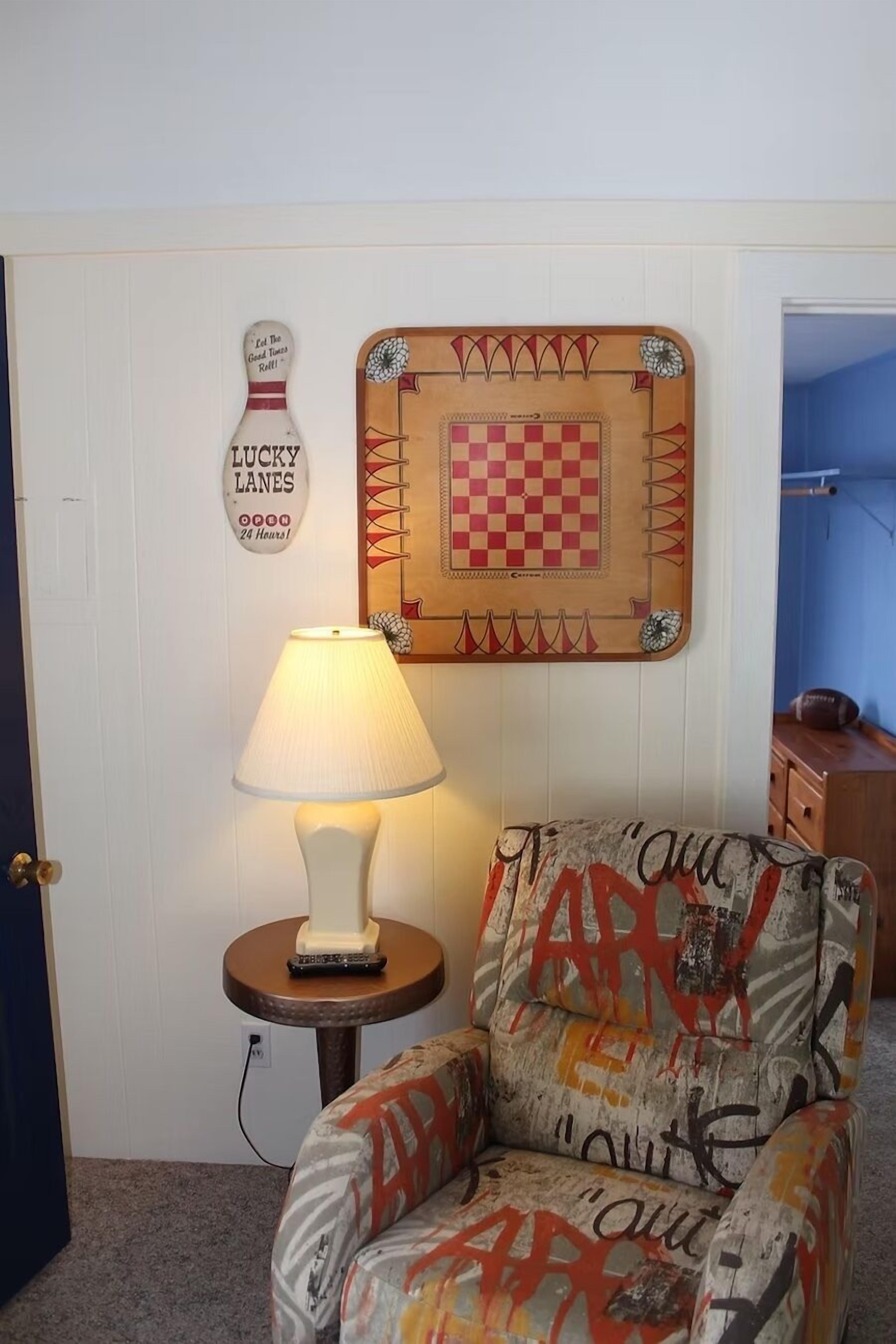 A room with a bowling pin, a checkered board, and a lamp on a small table.
