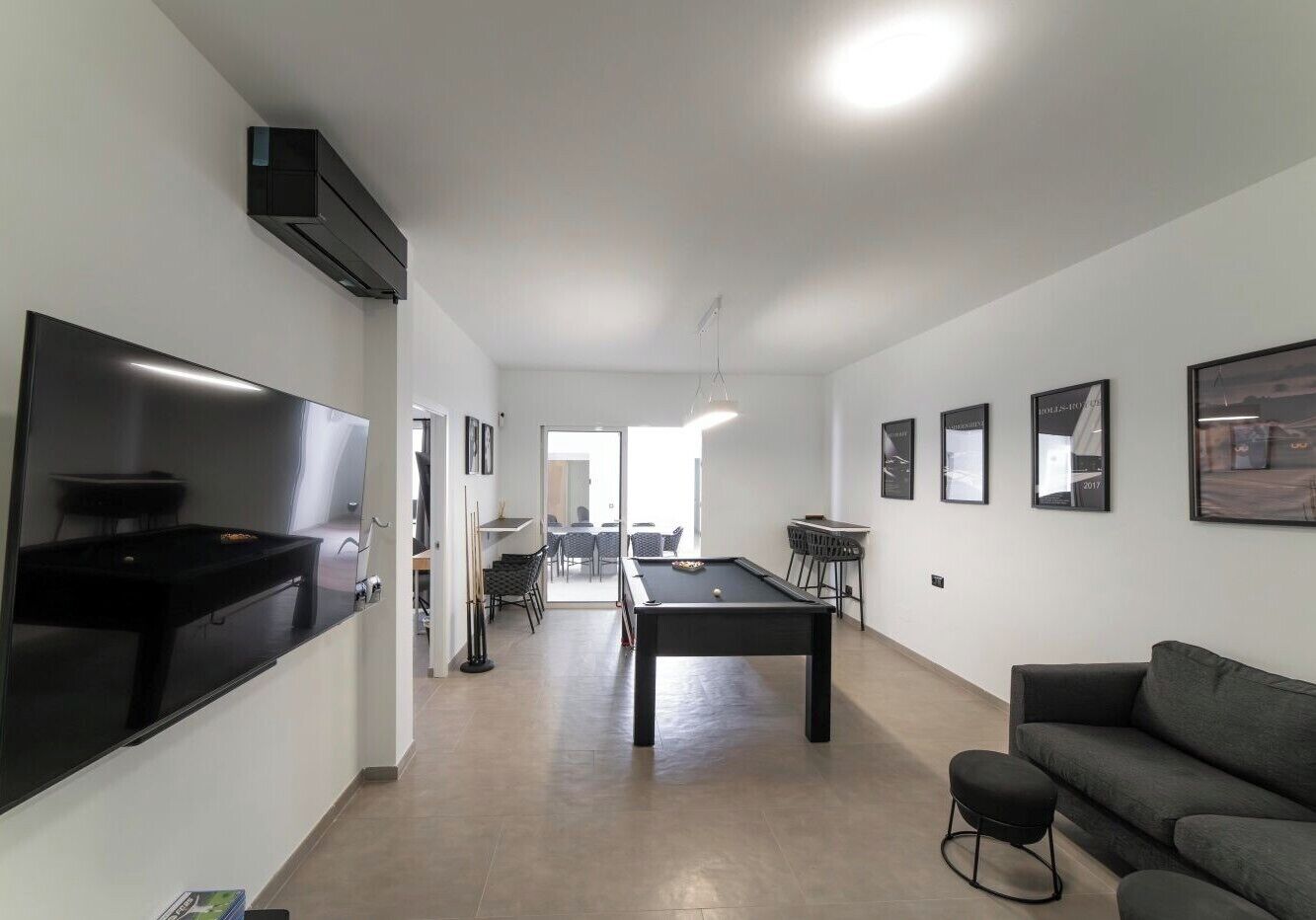 Uma sala de estar moderna com mesa de bilhar, um sofá e uma área de jantar com cadeiras e uma mesa.