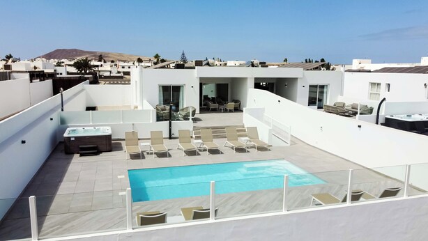 A rooftop pool area with a hot tub, lounge chairs, and a view of the cityscape. - Luxury, High-Standard Villa with Hot Tubs, Air Con & Pool - Sleeps 8 (Playa Blanca)