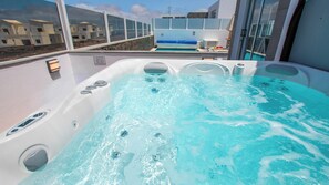 Boblebad med udsigt til en pool og bygninger i baggrunden.