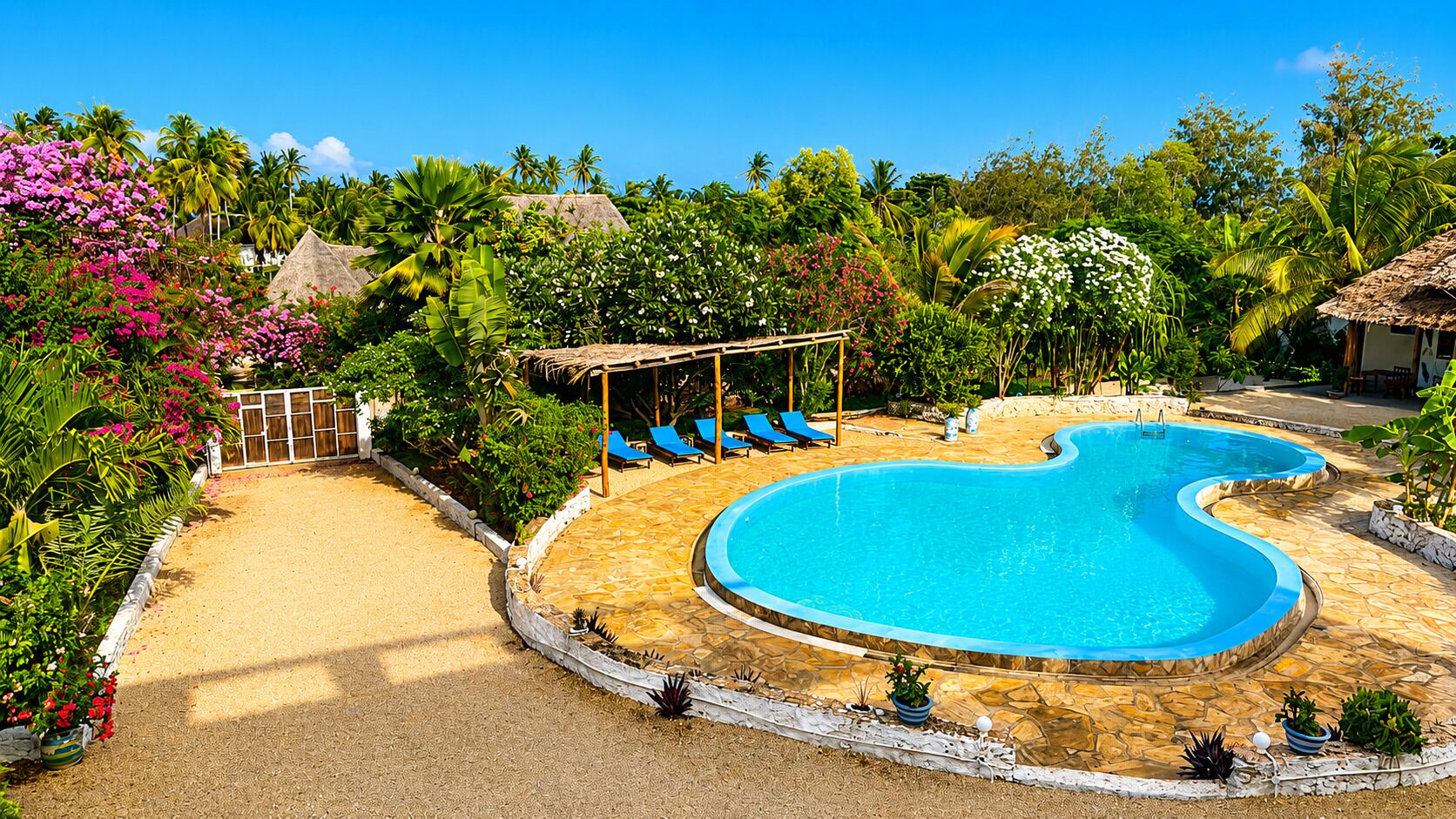 A swimming pool with a unique shape, surrounded by a stone deck and lush tropical vegetation.